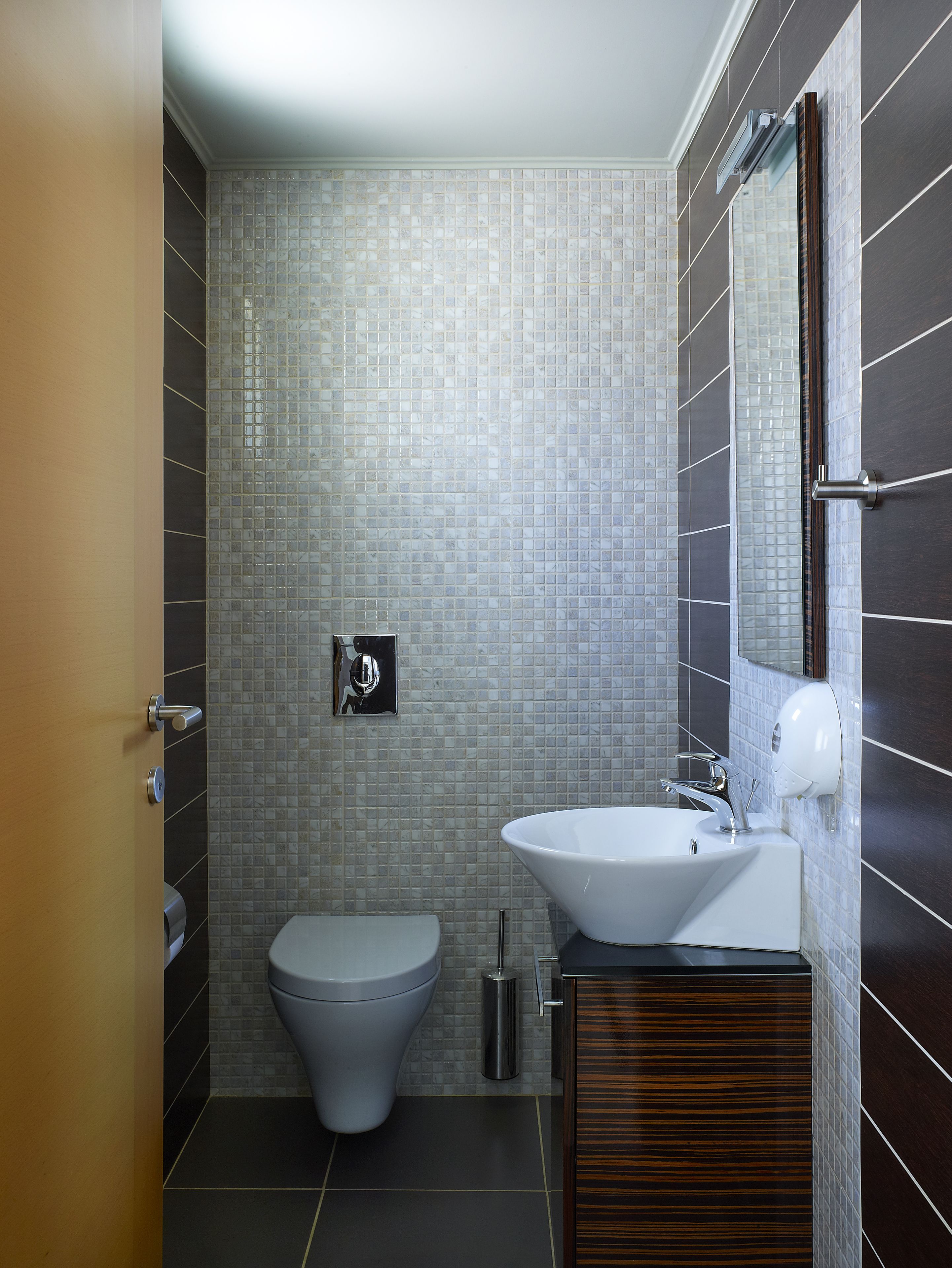 A modern bathroom with a toilet, sink, and mirror.