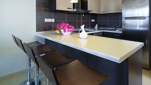A modern kitchen with a central island, stainless steel appliances, and pendant lighting. - Macaris Suites and SPA (Rethymno)
