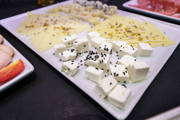 Diversos queijos e um tomate num prato branco.