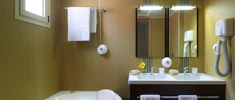 A bathroom with a bathtub, two sinks, a mirror, a towel rack, and a hairdryer.