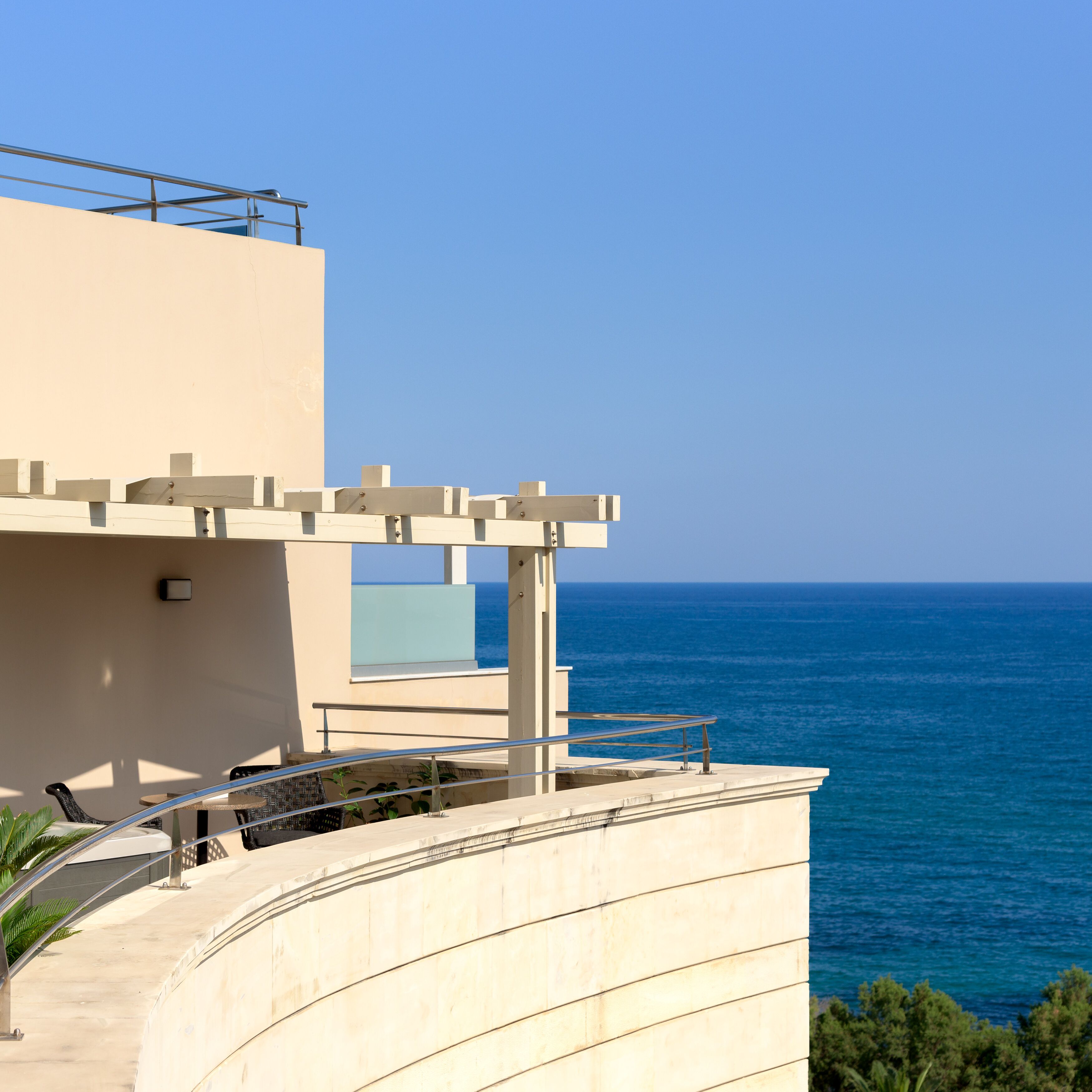 A modern building with a curved balcony overlooking the sea.