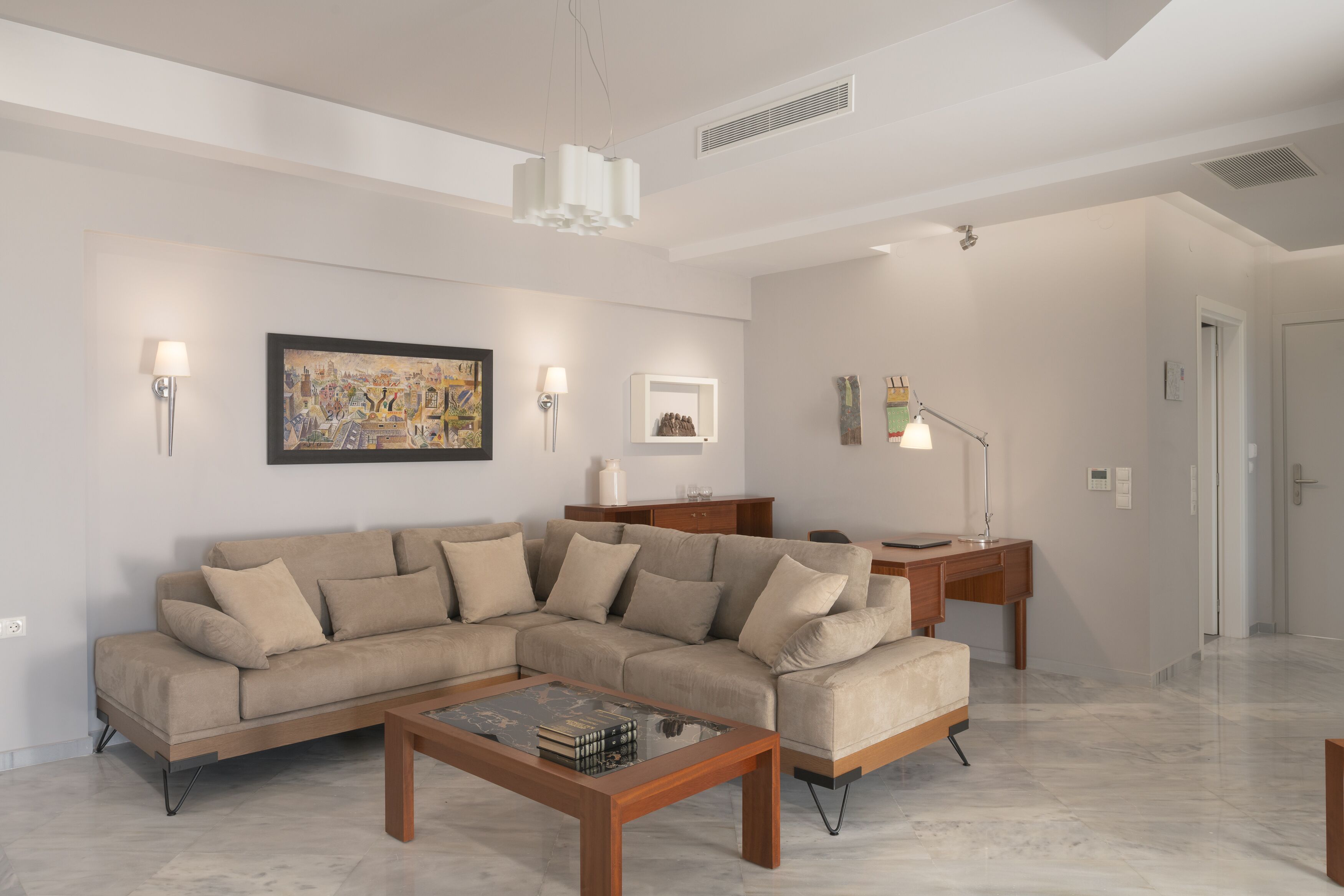 A modern living room with a sectional sofa, a wooden coffee table, and a desk with a lamp.