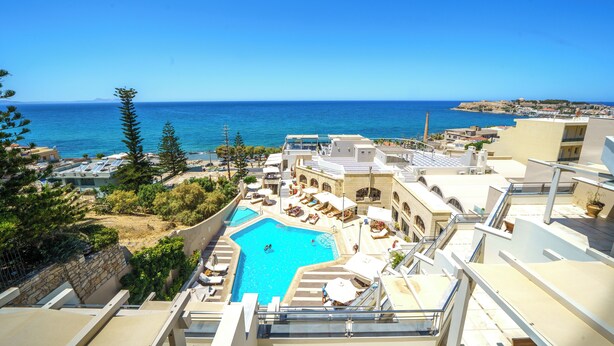 A rooftop pool with a view of the sea, surrounded by buildings and trees. - Macaris Suites and SPA (Rethymno)