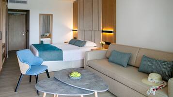 A modern hotel room with a bed, a sofa, a small table with fruit, a chair, and a mirror.