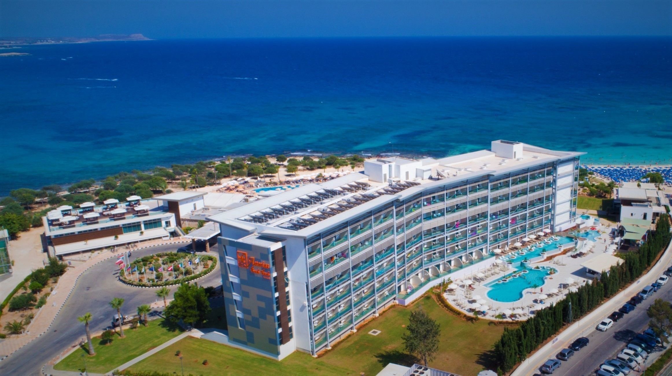 Een hotel met meerdere verdiepingen, een zwembad en uitzicht op het strand.