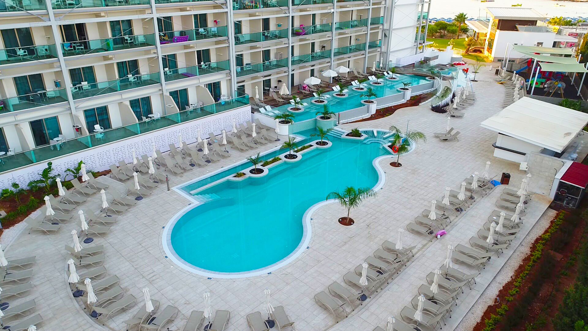 Un hôtel doté d'une grande piscine, de nombreux balcons et d'espaces extérieurs aménagés pour se détendre.