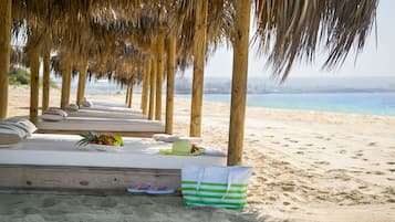 En la playa, arena blanca, sillas reclinables de playa, sombrillas