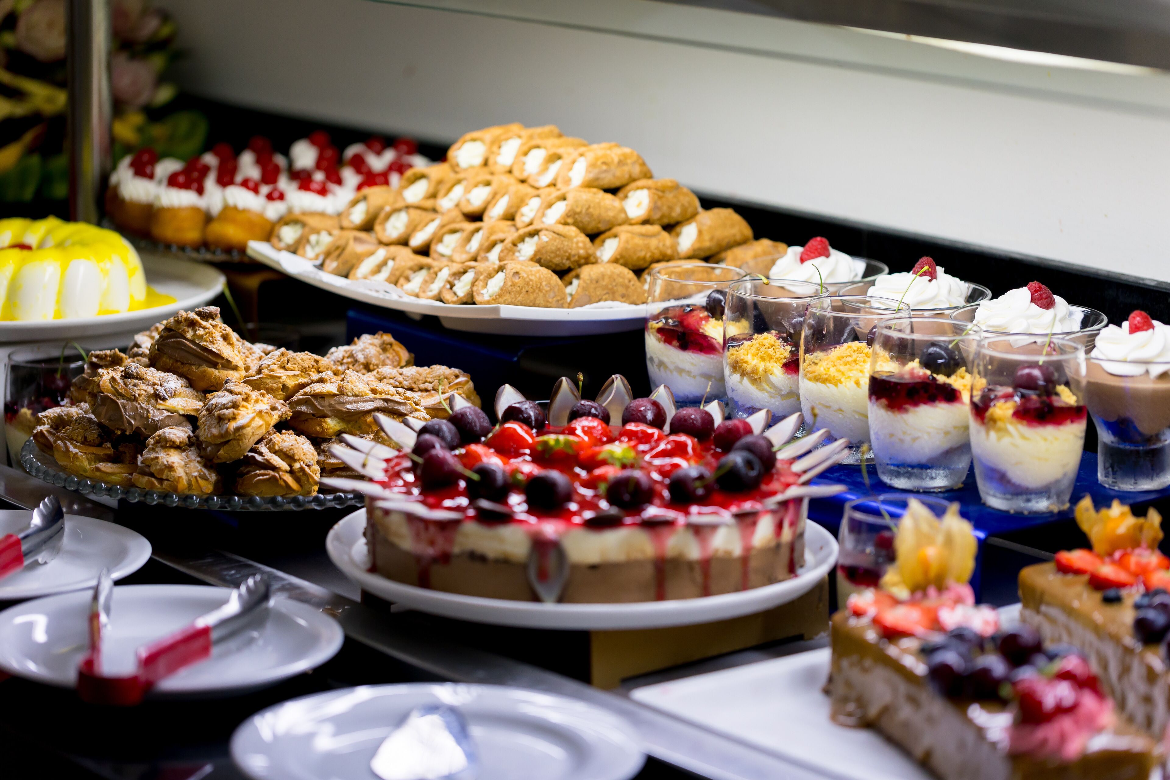 Un buffet proposant une variété de desserts, notamment des gâteaux, des pâtisseries et des plats agrémentés de fruits.