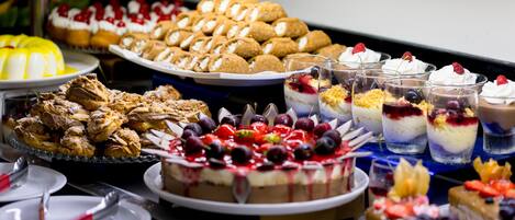 Un buffet proposant une variété de desserts, notamment des gâteaux, des pâtisseries et des plats agrémentés de fruits.