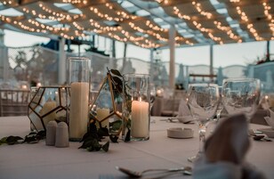 Una mesa dispuesta para un evento formal, con velas, cristalería y candelabros geométricos de vidrio.