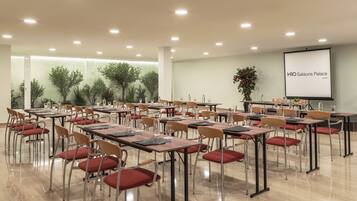 A conference room with tables, chairs, and a projector screen displaying 'H10 Salauris Palace'.