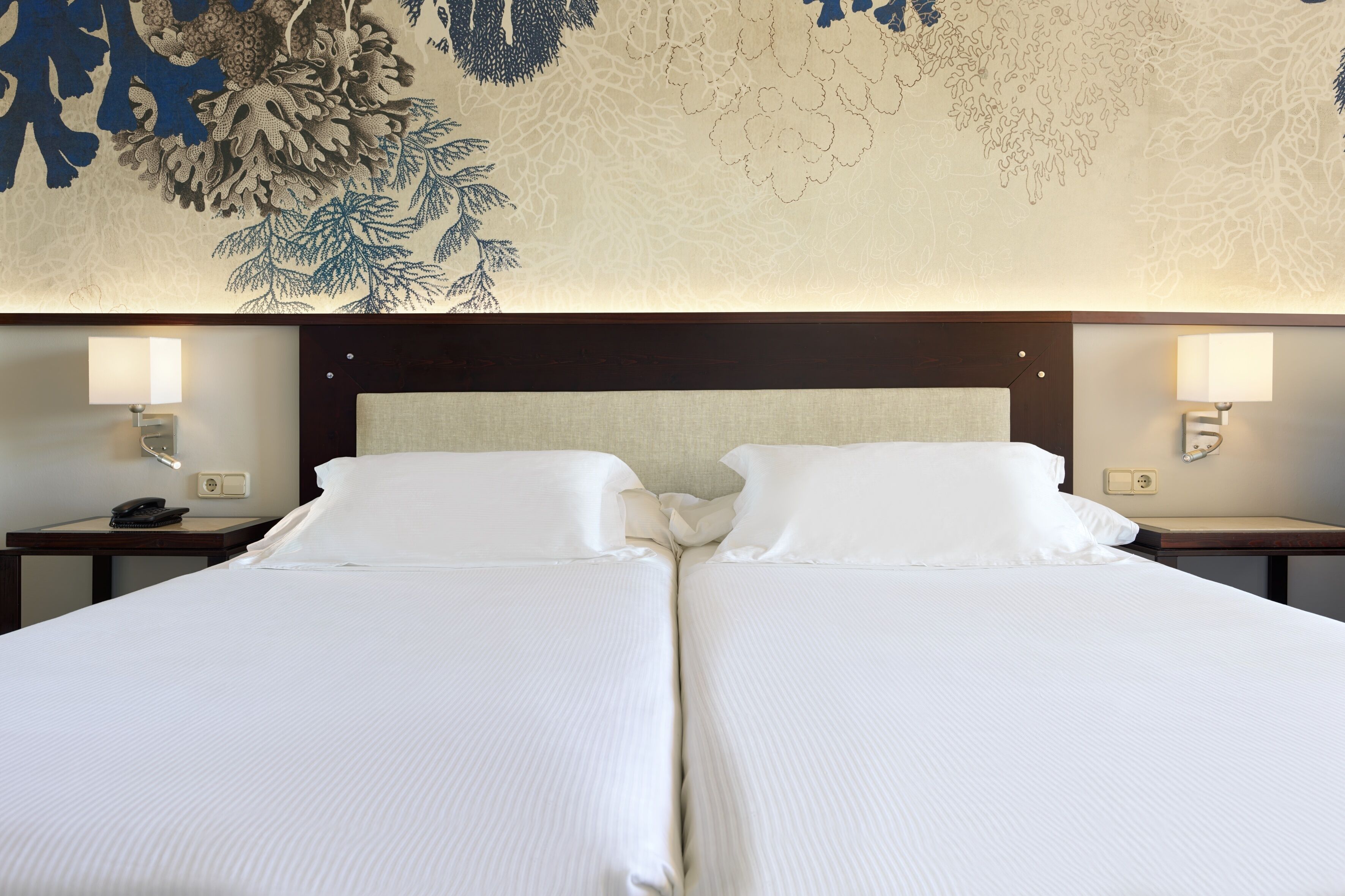 A hotel room with a large bed, two bedside tables, and a decorative wall mural.