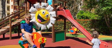A playground with a slide, climbing structures, and a colorful play area.