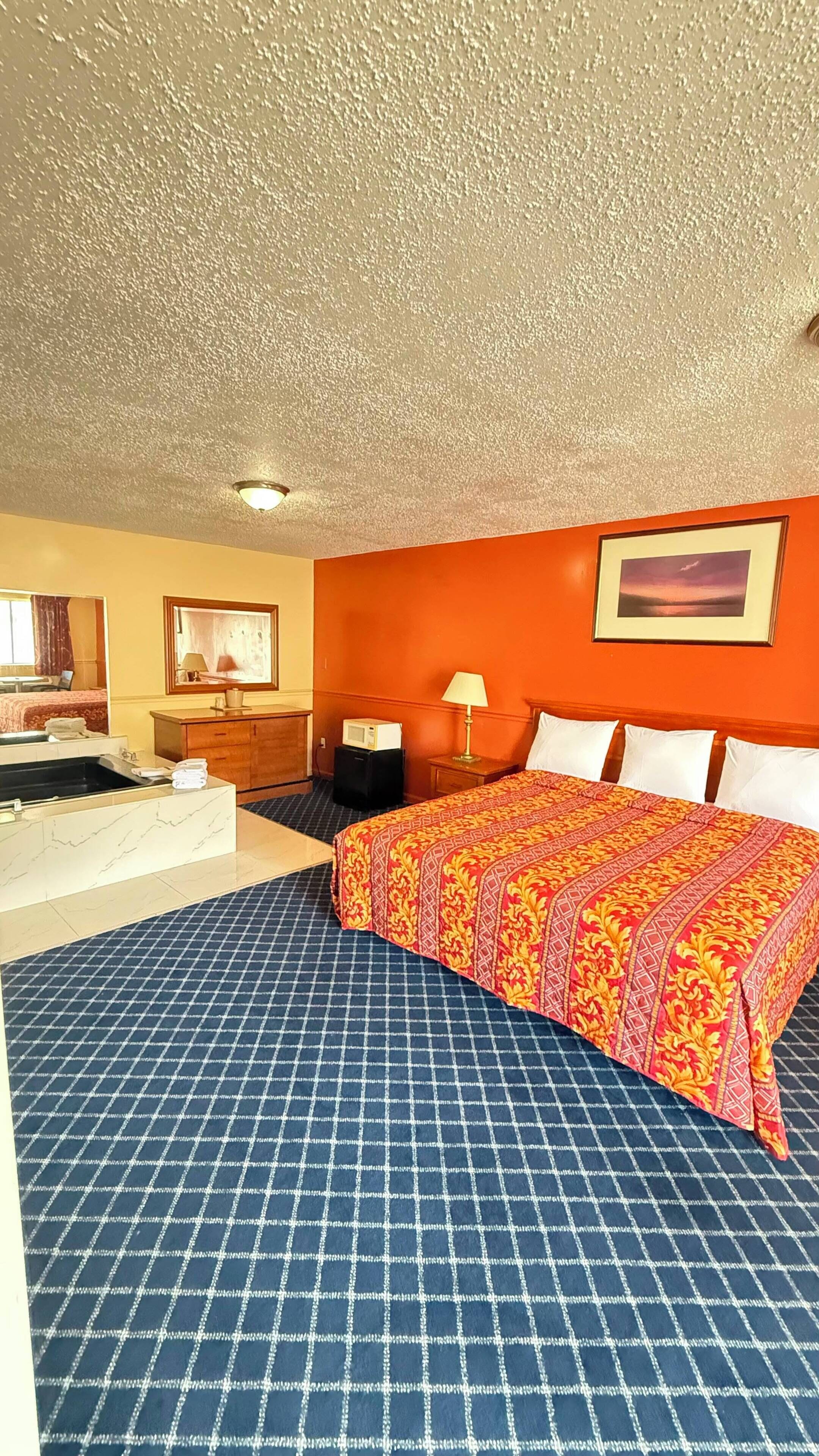 Ein Hotelzimmer mit einem großen Bett, einem Badezimmer mit Badewanne und einer Decke mit strukturierter Oberfläche.