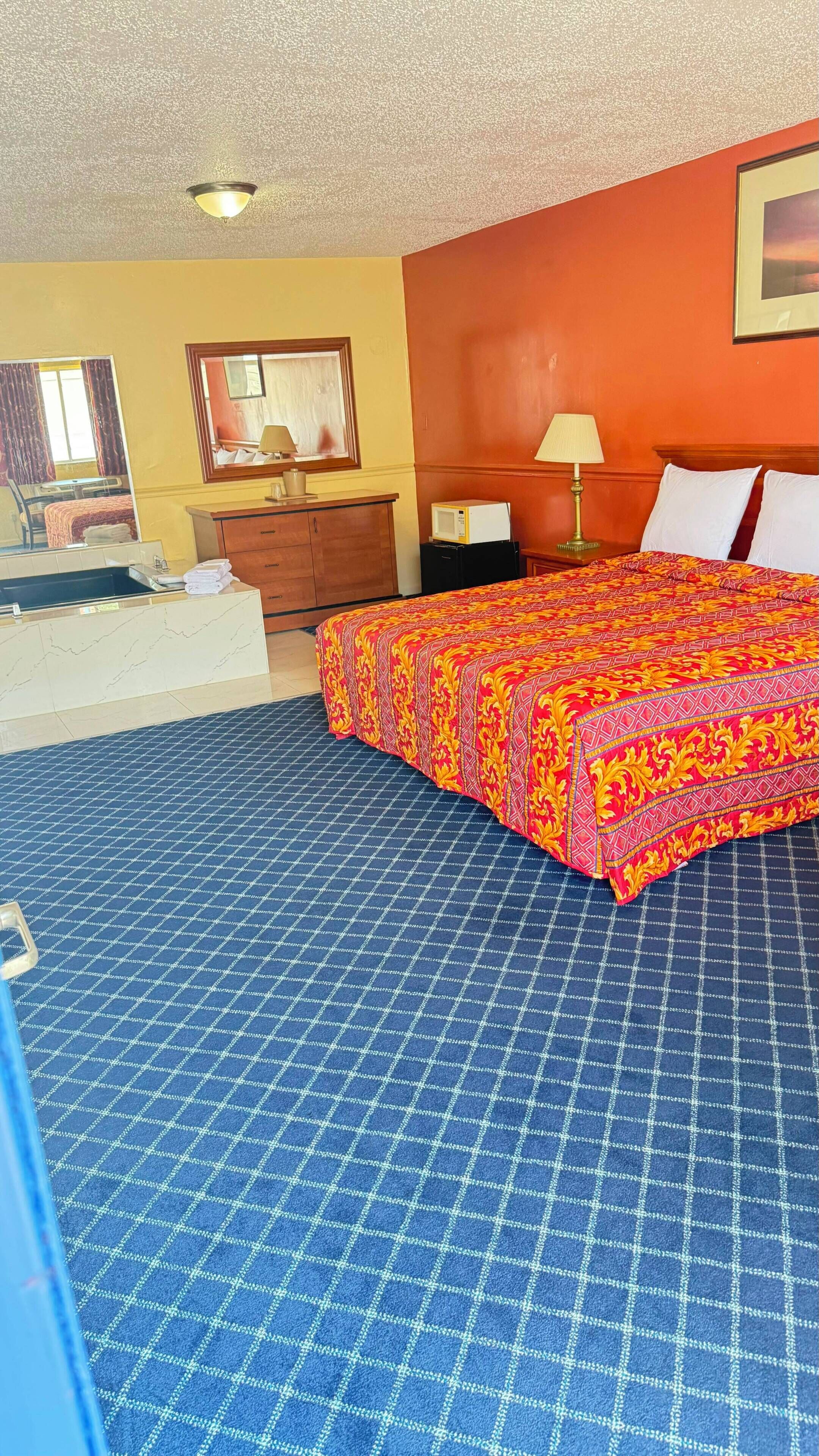 Una habitación de hotel con una cama, un tocador, un espejo y una ventana.