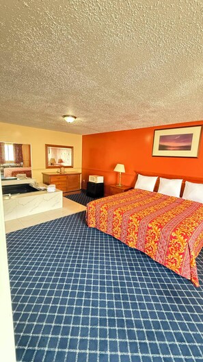 A hotel room with a bed, a bathroom, a desk, and a nightstand. - American Star Inn & Suites Atlantic City (Galloway)