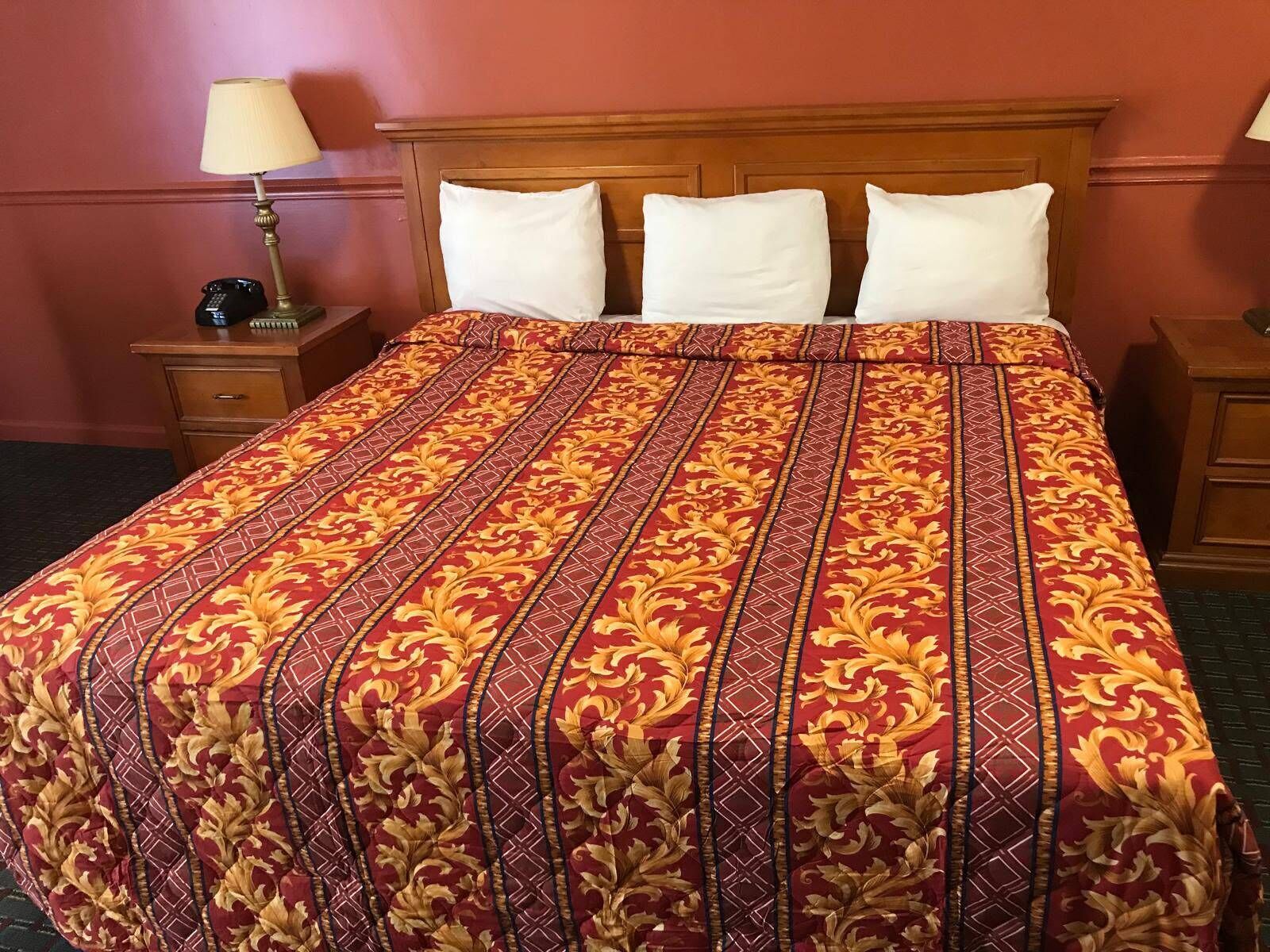 Ein Hotelzimmer mit einem großen Bett, einem Holzkopfstück, zwei Nachttischen und einer Lampe.