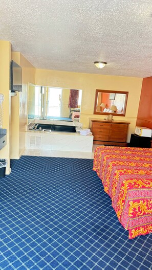 A hotel room with a bed, a dresser, a mirror, a sink, and a television. - American Star Inn & Suites Atlantic City (Galloway)
