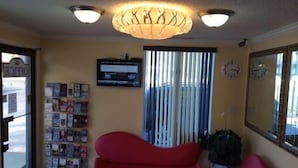 A reception area with a red sofa, a bulletin board with various items, a clock, and a ceiling light fixture.
