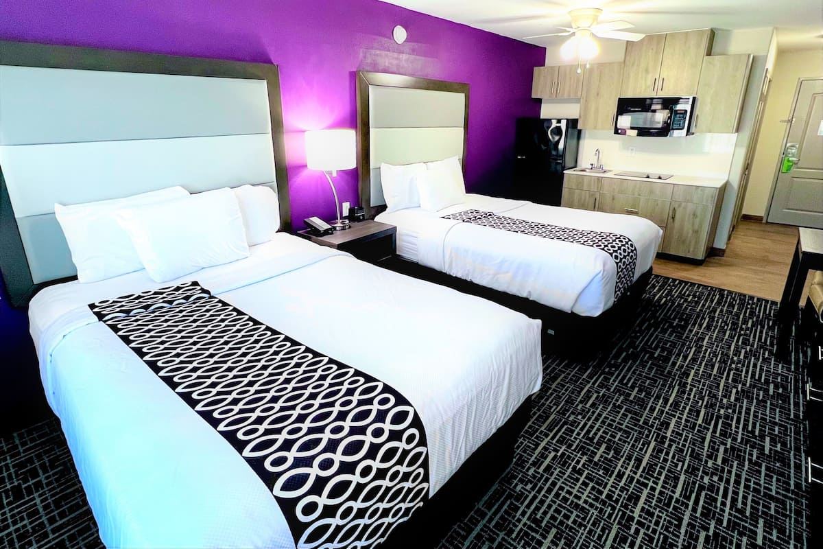 Une chambre d’hôtel avec deux lits, une kitchenette et une salle de bain.