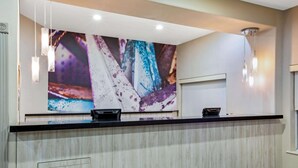 Een receptiebalie met een modern ontwerp, afgewerkt met licht hout en een groot abstract kunstwerk erboven.