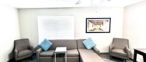 A modern living room with a sectional sofa, two armchairs, a small table, and a ceiling fan.