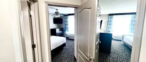 Une chambre d’hôtel avec un lit, une commode, un ventilateur de plafond et une fenêtre avec des rideaux.