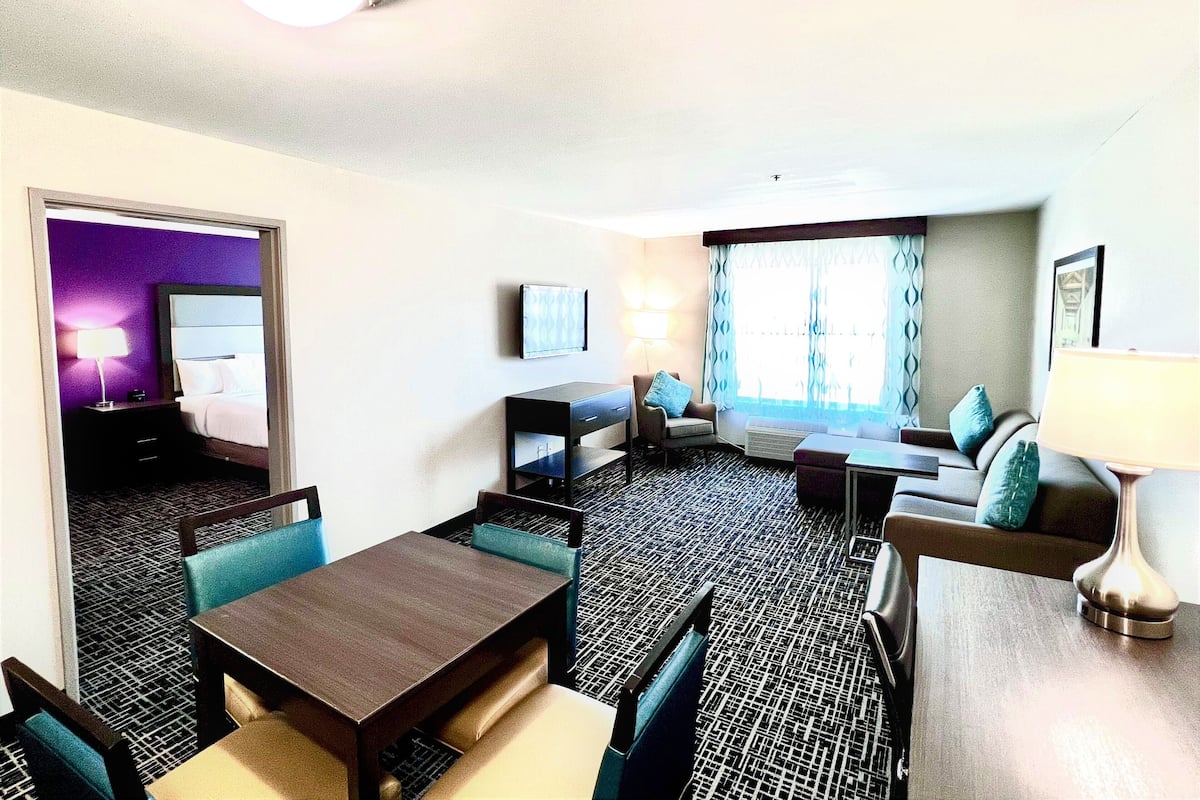 Une chambre d’hôtel équipée d’un lit, d’un bureau, d’une chaise, d’un canapé et d’une télévision.