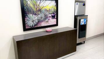 A reception desk with a flat-screen TV mounted above it, displaying a garden scene.
