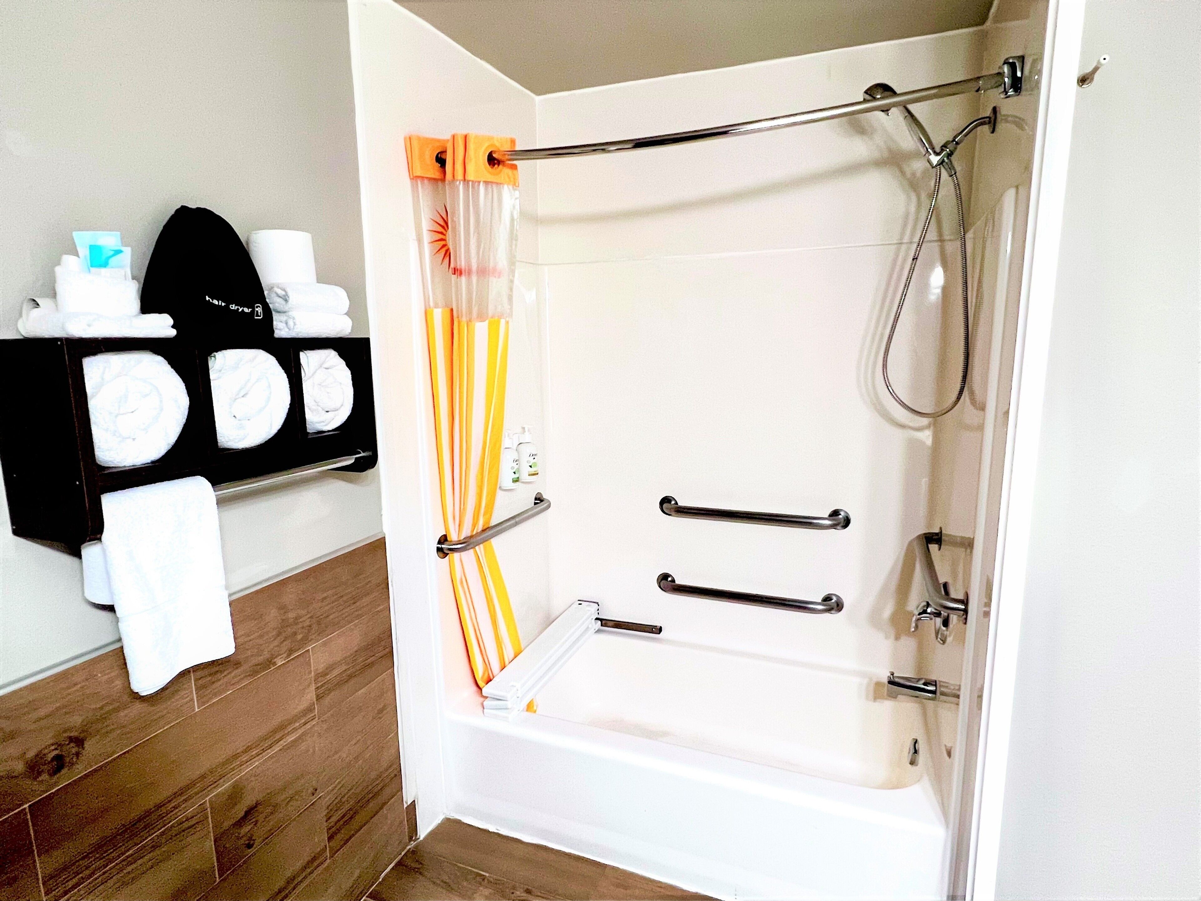 A bathroom with a shower, a towel rack with multiple towels, and a hand dryer.