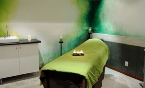 Una habitación con una cama, un lavabo y una pared verde.
