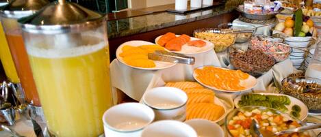 A buffet with various food items and beverages, including fruits, vegetables, and a large punch bowl.