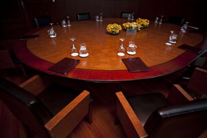 Un salón de conferencias con una mesa redonda, sillas y centros de mesa con flores.