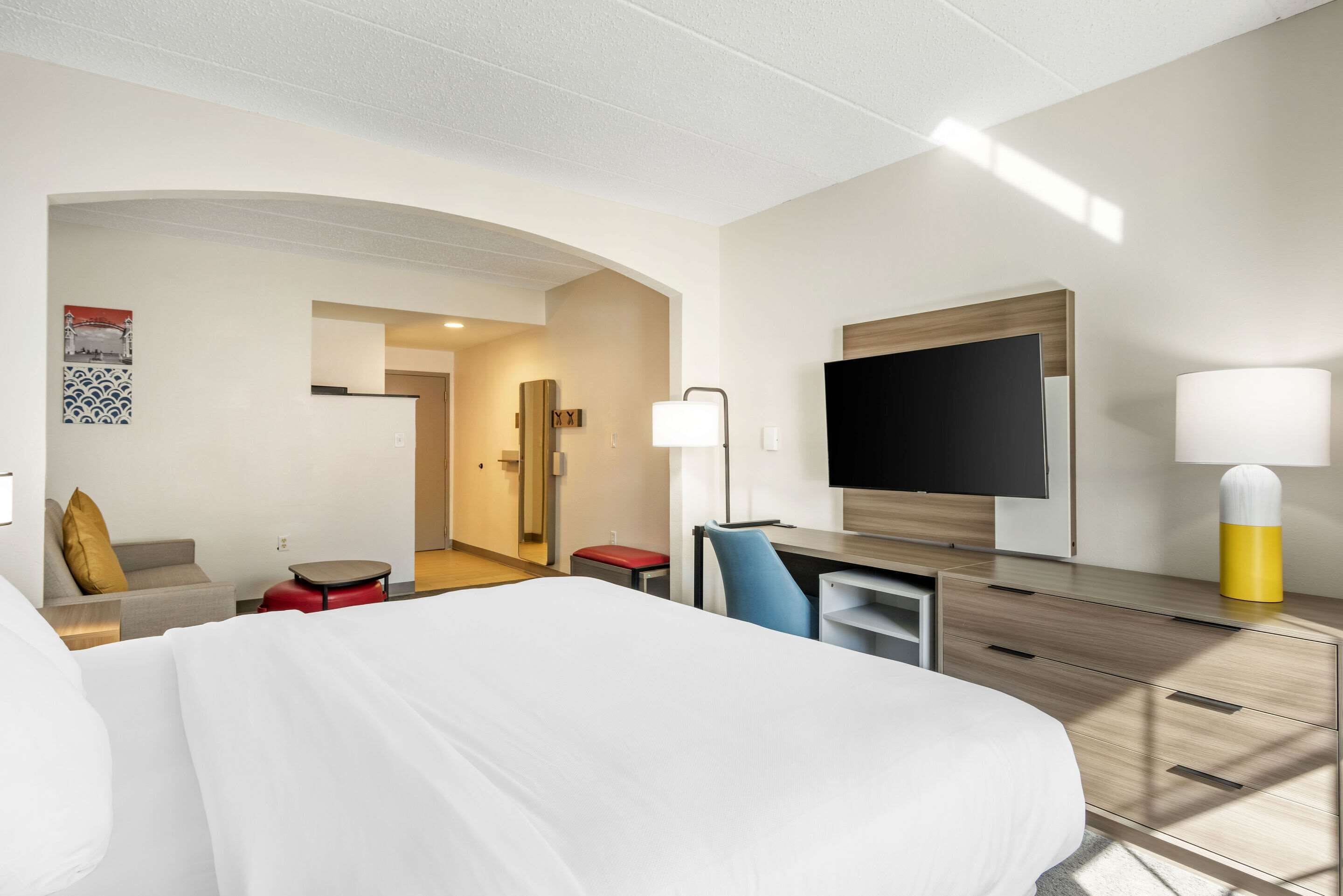 Une chambre d’hôtel avec un grand lit, un bureau, une chaise, une télévision et une lampe.
