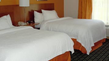 Una habitación de hotel con dos camas, una mesita de noche con lámpara y un teléfono.
