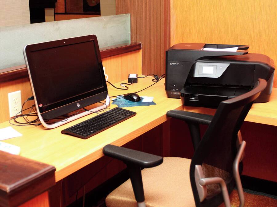 Una scrivania di legno con un laptop, un computer fisso, una stampante e una sedia.