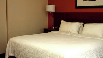 A neatly made bed with white linens in a hotel room.