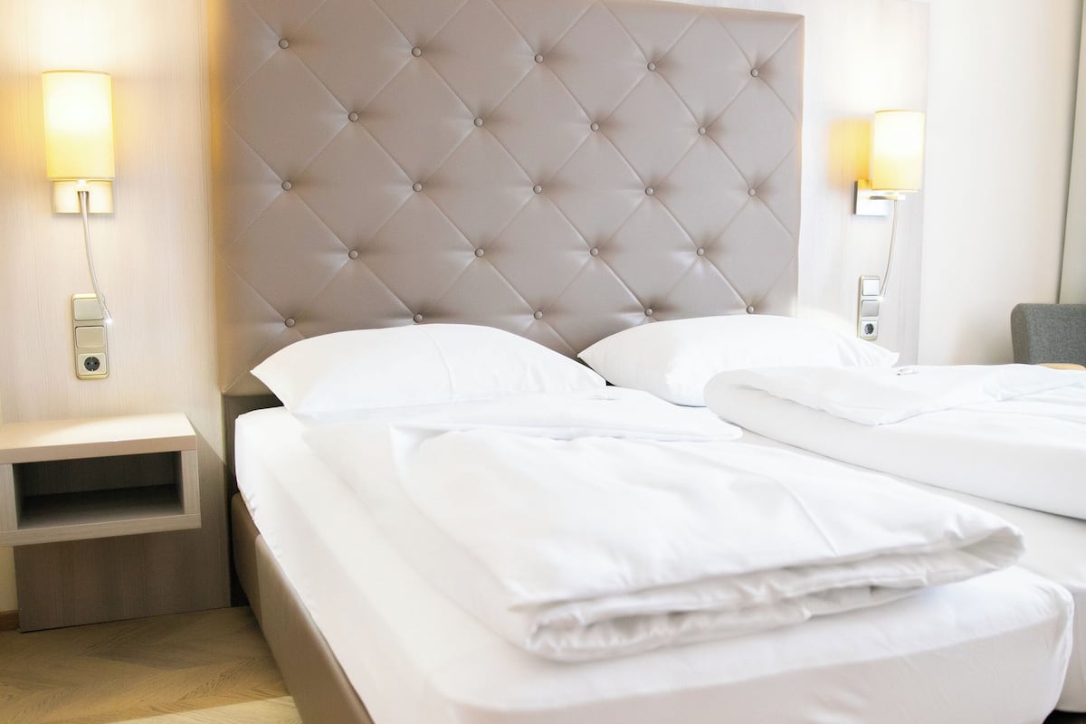 A hotel room with a large bed, two bedside tables, and wall-mounted lamps.
