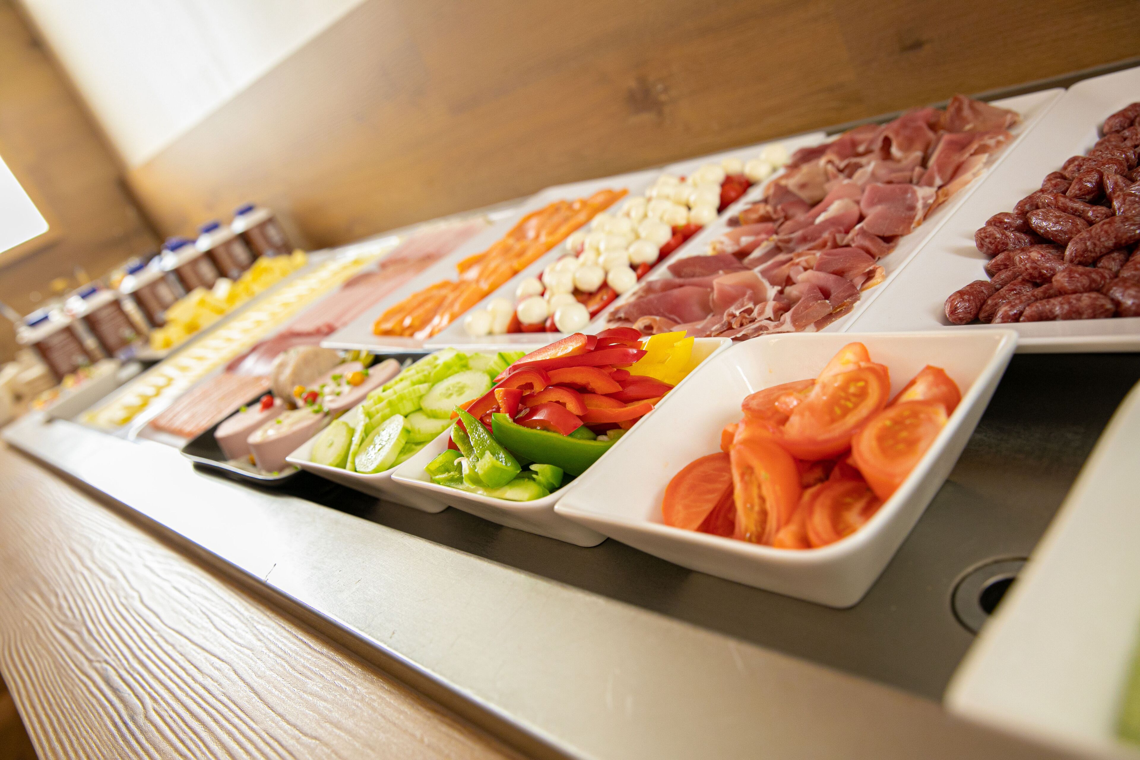A buffet with various food options including meats, cheeses, and vegetables.