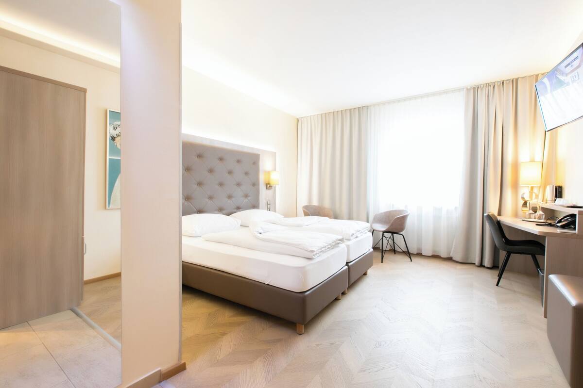 A hotel room with a double bed, a desk, and a chair.