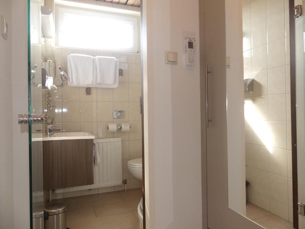 Une salle de bain avec une douche à parois de verre, un lavabo, des toilettes et un porte-serviettes.