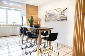 A modern dining area with a wooden table, black chairs, and a potted plant. - Das Reinisch Hotel - near Vienna Airport (Schwechat)