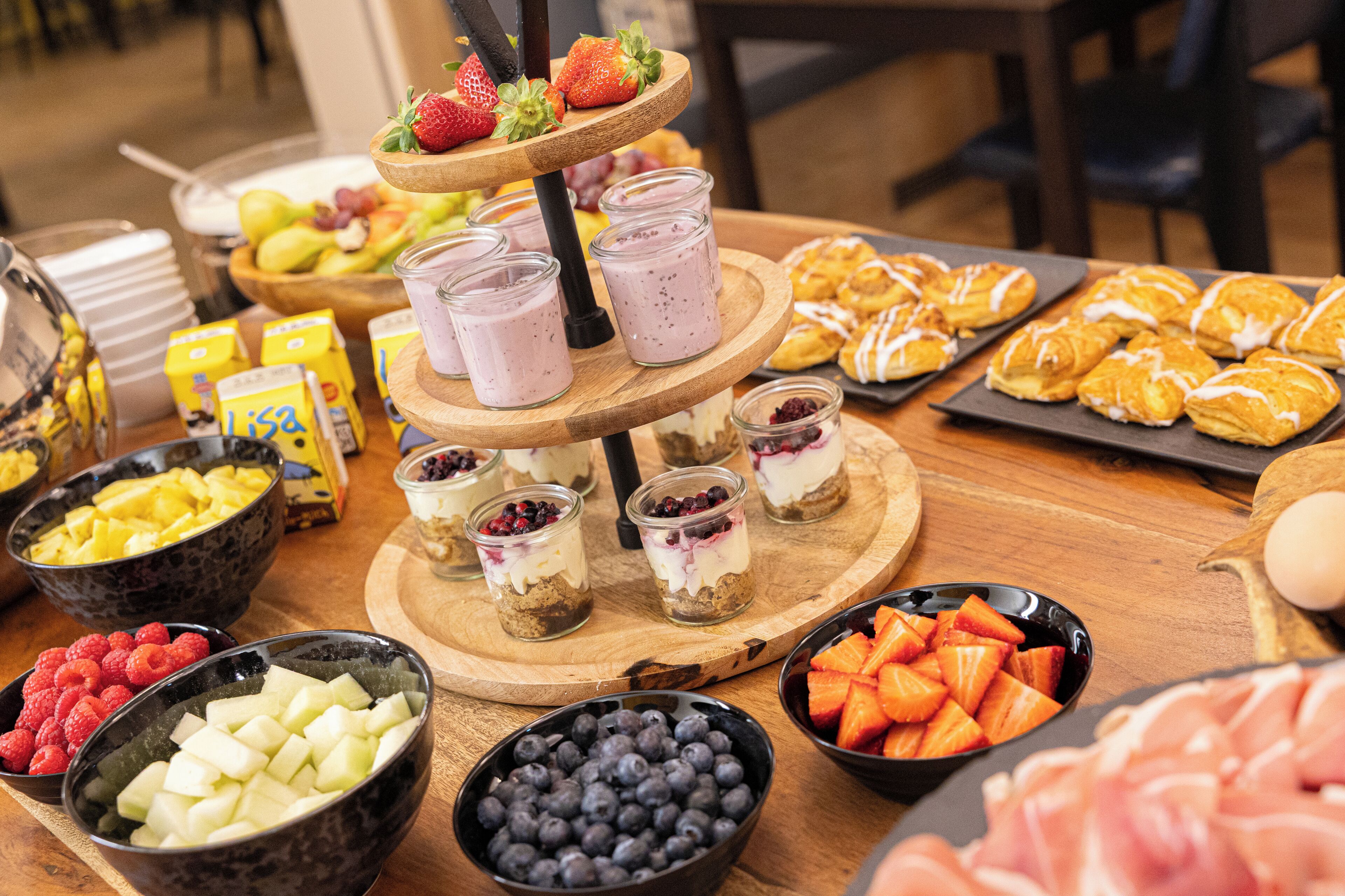 A buffet with various food items including fruits, pastries, and desserts.