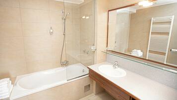 A modern bathroom with a glass-enclosed shower, a freestanding bathtub, and a vanity with a mirror.