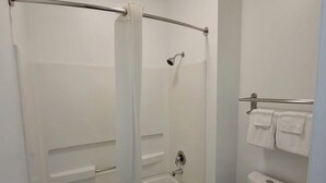 A bathroom with a shower, toilet, and towel rack. - Scottish Inns & Suites Forney/East Dallas (Forney)
