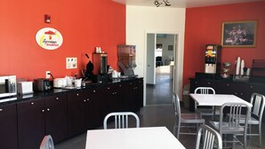 A restaurant with a red wall, a Superstart breakfast sign, a coffee machine, and a painting. - Scottish Inns & Suites Forney/East Dallas (Forney)
