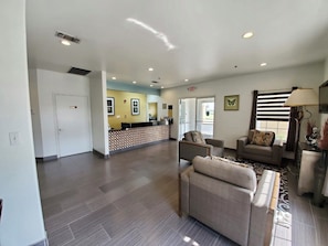 A spacious lobby with a reception desk, seating area, and a door leading to another room.