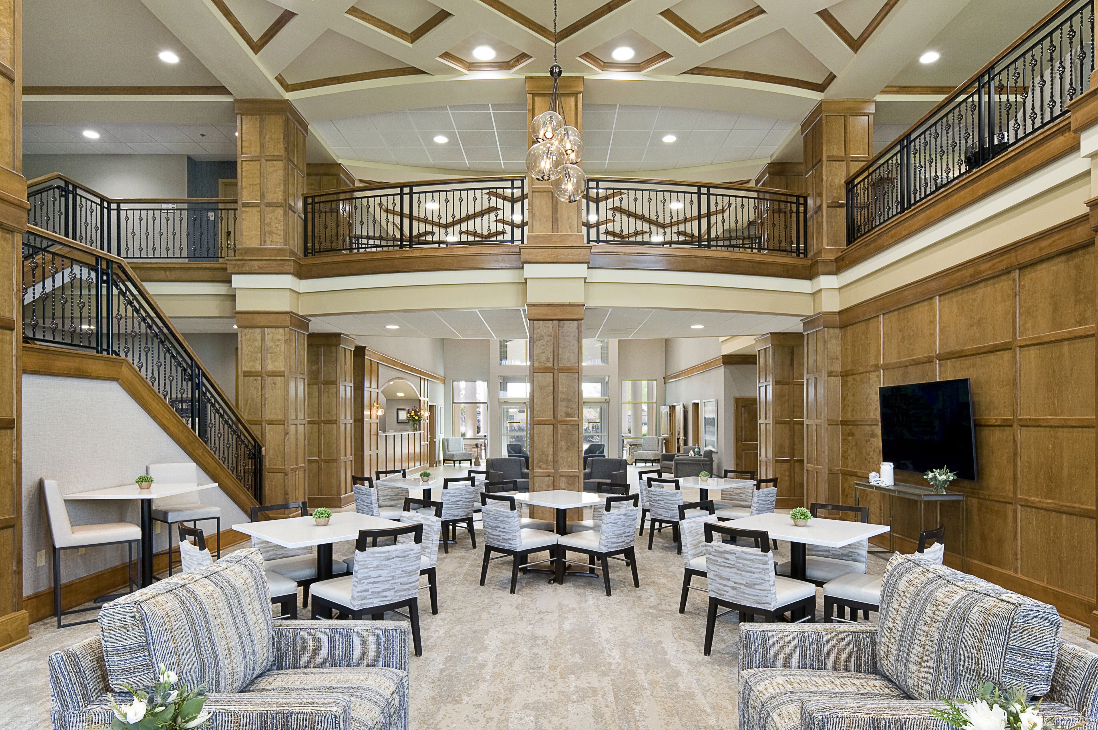 A spacious multi-level lobby with a central staircase, multiple seating areas, and a large chandelier.