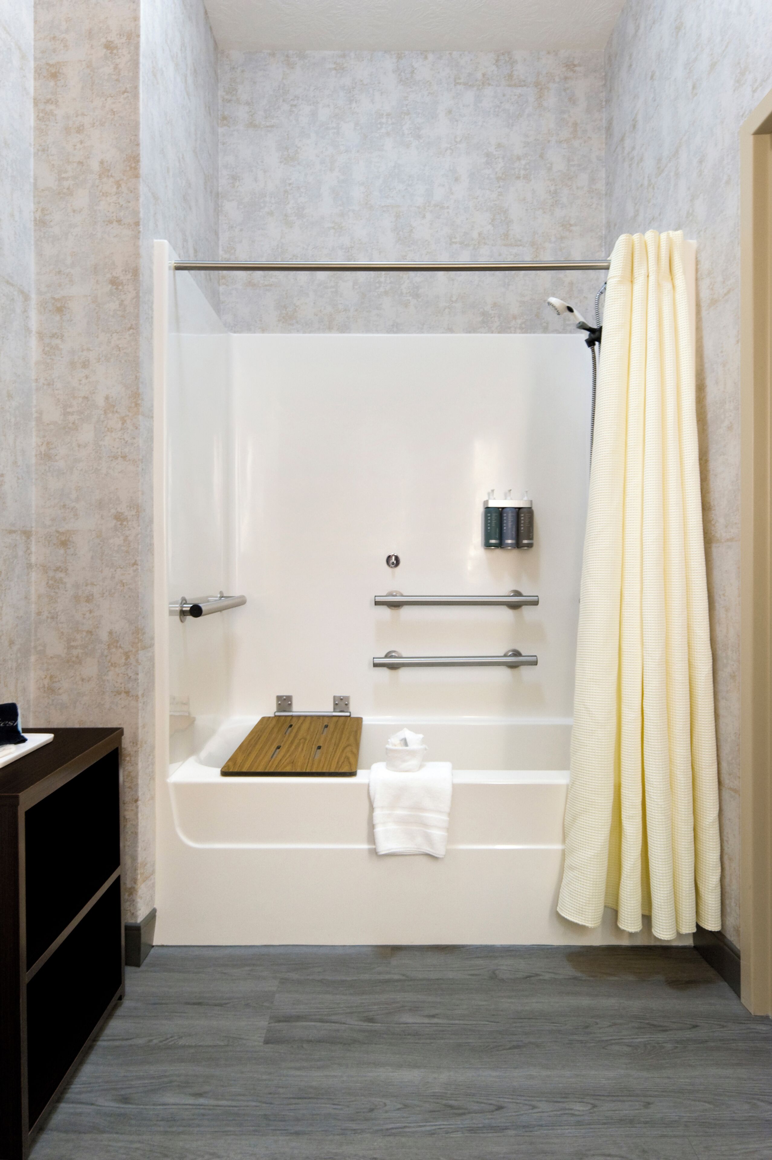 A bathroom with a bathtub, a shower curtain, a towel rack, and a shelf.