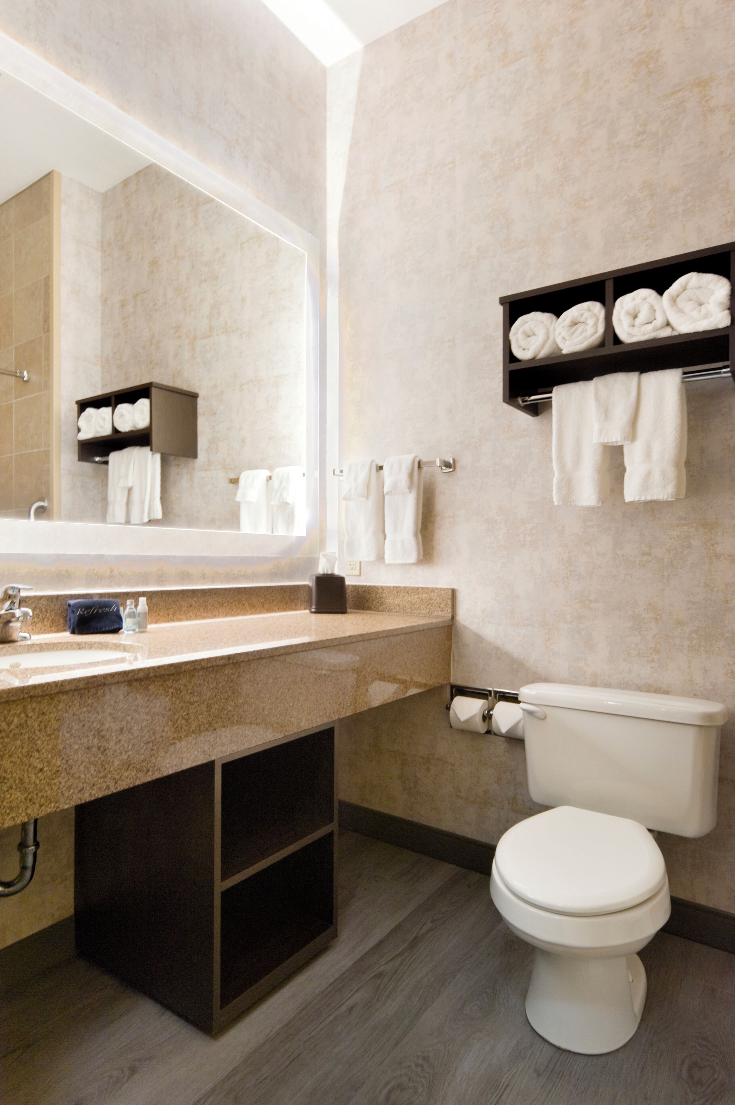 Ein Badezimmer mit Waschbecken, Spiegel, Handtuchhalter und Toilette.